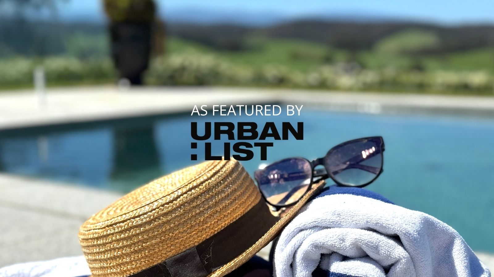 Luxury poolside escape at Scotch Hill Truffle Farm, Neerim South — straw hat and sunglasses beside the infinity pool with mountain views of West Gippsland.